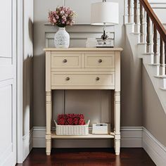 a white table with flowers and a basket on it in front of a stair case