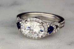 a diamond and blue sapphire ring on a marble surface with the center stone surrounded by diamonds