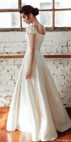 a woman standing in front of a window wearing a wedding dress