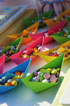 there are many small boats that have candy in them on the table next to each other