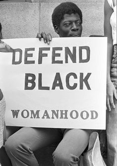 black women holding a sign that says defend black womanhood