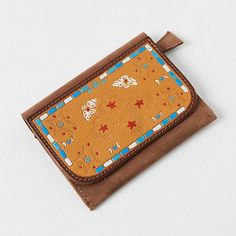 an orange wallet with blue and white designs on it's front pocket, sitting on top of a white surface