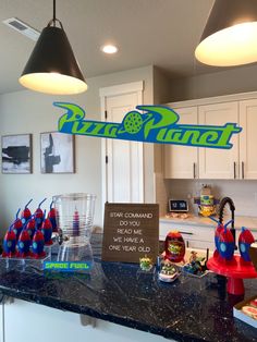 a kitchen counter topped with lots of food and drinks on it's side, next to a sign that says pizza planet