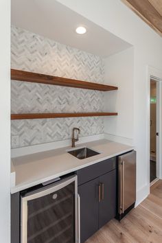 an empty kitchen with wood floors and white walls, along with stainless steel dishwasher