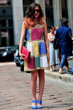 a woman in a multicolored dress is standing on the street