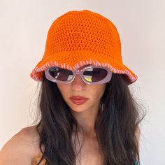 a woman wearing an orange crocheted hat and sunglasses