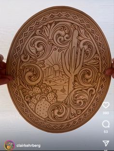 a person holding up a wooden plate with designs on it