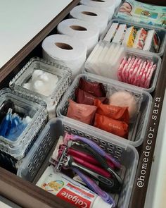 an organized drawer filled with toilet paper, scissors and other household care items in plastic containers