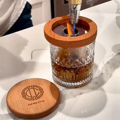 a glass jar with a brush in it sitting on a counter next to a wooden coaster