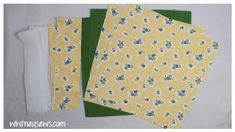 three pieces of yellow fabric with blue flowers on them and one piece of green paper