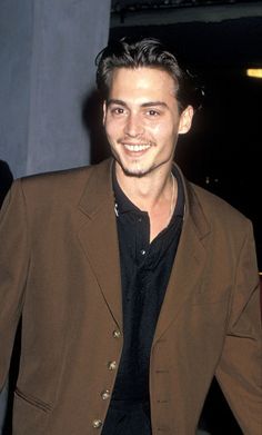 a man in a brown suit smiling at the camera