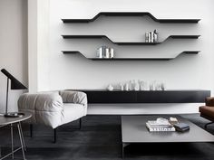 a living room with two couches and a coffee table in front of a wall mounted shelving unit