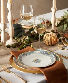 a table set with plates, silverware and candles