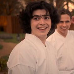 two men in white robes are smiling at the camera and one man has his hair pulled back