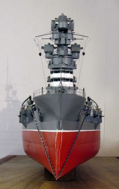 a model of a large ship on display in a museum setting with white walls and wooden flooring