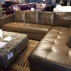 a brown leather couch and ottoman in a store