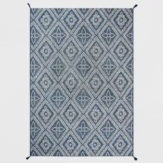 a blue and white rug with an intricate design on the bottom, in front of a gray background