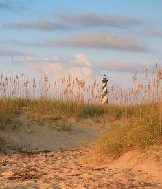 a lighthouse in the sand with sea oats around it