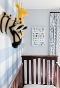 a baby's room with blue and white checkered wallpaper, wooden crib bedding, and striped curtains