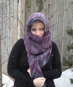 a woman standing in the snow wearing a purple scarf and black coat with her hands on her hips