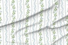 a white and green striped fabric with leaves on the side, in front of a ruler