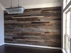 an empty room with wood paneling on the wall and chandelier hanging from the ceiling