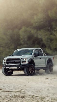 a white truck driving down a dirt road