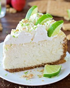 a slice of cheesecake with limes and whipped cream on top is sitting on a plate