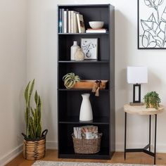 a black bookcase in a living room next to a table and potted plant