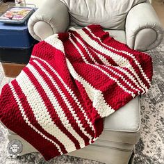 a red and white crocheted blanket sitting on top of a chair next to a couch