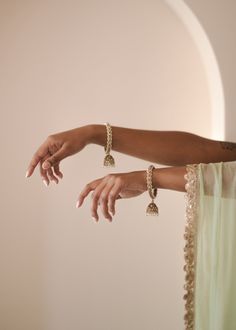 Adorn your wrists with the refined elegance of our antique gold Saavana Bangles, featuring almond-shaped gems and cream stones. The dangling jhumkas add a touch of sophistication, perfect for standalone chic or curated bangle ensembles. Includes 2 bangles. Elegant Jhumkas With Gota Work, Elegant Jhumkas With Gota Work For Diwali, Elegant Festive Brass Chandbalis, Bohemian Brass Jhumkas For Weddings, Elegant Brass Jhumkas For Rituals, Elegant Festive Jhumkas With Gota Work, Brass Jewelry For Wedding And Navratri, Elegant Latkans Jewelry For Navratri, Elegant Brass Chandbalis For Festive Occasions