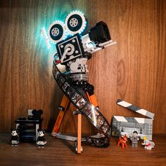 a wooden table topped with legos and toy cars next to a movie projector