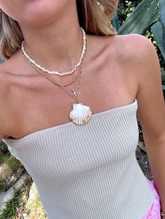 Our Shell Yeah Gold Filled Necklace is the perfect necklace for the beach lover. This necklace features 24k Gold Filled chain, real sea shell with gold plated edges, and lightweight for layering. Style this necklace with your favorite summer dress, your next beach trip with your fave bikini, or with your fave graphic tee! Please be gentle with your shell ♡ All accessories are final sale. Gold Ocean-inspired Necklaces For Beach Season, Beachy Gold Necklaces For Vacation, Gold Ocean-inspired Necklace For Beach Season, Gold Shell For Beach Season, Summer Beach Necklace With Clavicle Chain, Summer Beach Necklaces With Pearl Charm, Summer Beach Jewelry With Pearl Chain, Summer Beach Pearl Chain Jewelry, Gold Strand Shell For Vacation