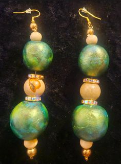 5" in length; lightweight and comfortable. The metallic green and gold rounds beads are both hand sculpted and hand painted with alcohol inks and a metallic glaze. The other components include a beige picasso jasper, golden aurora borealis rhinestone rondelles, bone and shiny gold tone beads. The beads are suspended on a heavy duty beading wire and support from a thin, gold tone, sterling silver (925 hypoallergenic) fishhook ear wire which has a silicone back to guard against loss. Very funky jewelry from the Atelier of Kat Kouture! Jewellery Shop Design, Metallic Glaze, Turquoise Western, Picasso Jasper, The Atelier, Dusters, Funky Jewelry, Beading Wire, Western Jewelry