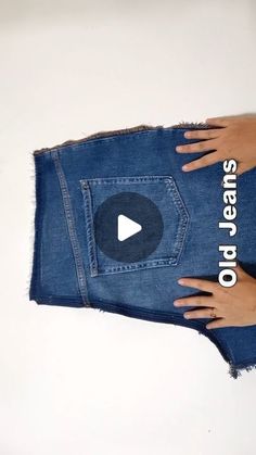 someone's hand holding up a pair of blue jeans with the words on it