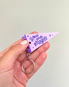 a hand holding a purple keychain that says you are magic on the front