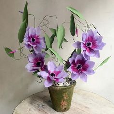 purple flowers are in a green vase on a table