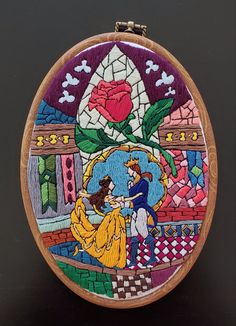 a hand embroidered beauty and the beast scene on a wooden hoop with stitching in it