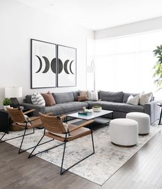 a living room filled with furniture next to a large window and potted plant on top of a hard wood floor