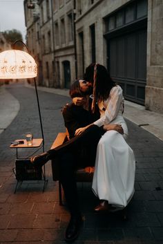 a man and woman sitting on a bench in the middle of an alleyway kissing