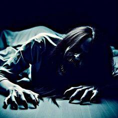 a woman laying on top of a bed in the dark