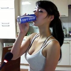 a woman drinking from a can in a kitchen