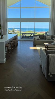 a living room filled with furniture and a large window overlooking the ocean in front of it