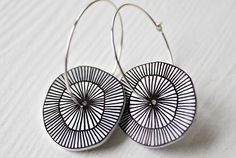 pair of black and white earrings with circular design on the front, hanging from silver earwires