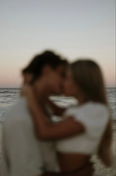 a man and woman kissing on the beach