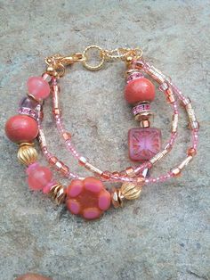 Beautiful Handcrafted Three Strand Women's/Teen Girl's Beaded Bracelet with Large Czech Picasso Floral Focal Bead, Beautiful Pink Jade, Ceramic beads, Gold Wavy Spacers, Rhinestone Rhondelles and Gold-Filled Spacers and Clasp. This Bracelet Will Delight Anyone Who Loves Pink.  These Czech Glass Beads are so Beautiful and Unique. Thank You for Looking and Please Message Me with Any Questions. Bead Colors: Pink Orange Gold Bracelet Length:  7 1/2" **Not Suitable for Young Children.     Beads Prese Bohemian Pink Beaded Bracelets From Czech Glass, Pink Czech Glass Beaded Bracelet With Colorful Beads, Pink Czech Glass Beaded Bracelets With Colorful Beads, Pink Beaded Bracelets With Czech Glass, Pink Bohemian Beaded Bracelets In Czech Glass, Pink Czech Glass Bracelets With Colorful Beads, Bohemian Pink Beaded Bracelets Czech Glass, Pink Czech Glass Bracelets With Spacer Beads, Pink Czech Glass Beaded Bracelets