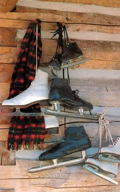 several pairs of ice skates are hanging on a wooden wall next to a scarf