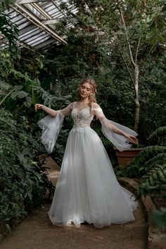 a woman in a white wedding dress is posing for the camera with her arms outstretched