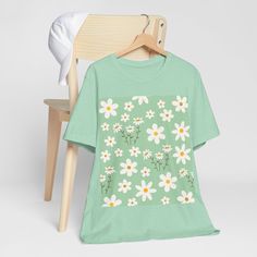 Made with soft cotton, this shirt features a charming daisy flower pattern on a refreshing spring mint green background. Embrace the joys of spring in style and comfort. This classic unisex jersey short sleeve tee fits like a well-loved favorite. These soft cotton t-shirts have-ribbed knit collars to bolster shaping. The shoulders are tapered for a better fit over time. Dual side seams hold the garment's shape for longer. .: Made with 100% Airlume combed and ring-spun cotton, a lightweight fabri Green Casual T-shirt For Spring, Casual T-shirt With Daisy Print For Spring, Light Green Short Sleeve Cotton Top, Light Green Cotton Short Sleeve Top, Spring Relaxed Fit Short Sleeve T-shirt, Relaxed Fit Short Sleeve T-shirt For Spring, Floral Print Short Sleeve T-shirt For Spring, Light Green Short Sleeve Tops For Spring, Summer Daisy Print Short Sleeve T-shirt