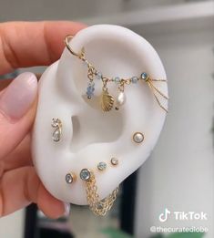 a person holding a fake ear with jewelry on it